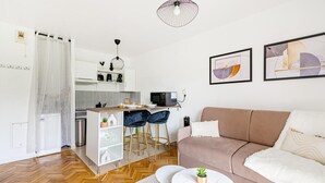 A modern living room with a sofa, a coffee table, and a kitchen area with a microwave. - Sweet cocoon at Disney (Montévrain)