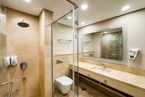 Une salle de bain moderne avec une douche à parois de verre, un lavabo avec un miroir et des toilettes.