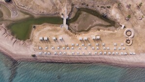 An aerial view of a coastal area with a row of white tents arranged in a linear fashion along the shoreline, a circular structure, and several small green areas that could be pools or ponds. - Xuru Stays I Homestyle 3BR Penthouse Pool & Beach View (El Gouna)