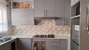 A compact kitchen with grey cabinets, a gas stove, and a microwave.