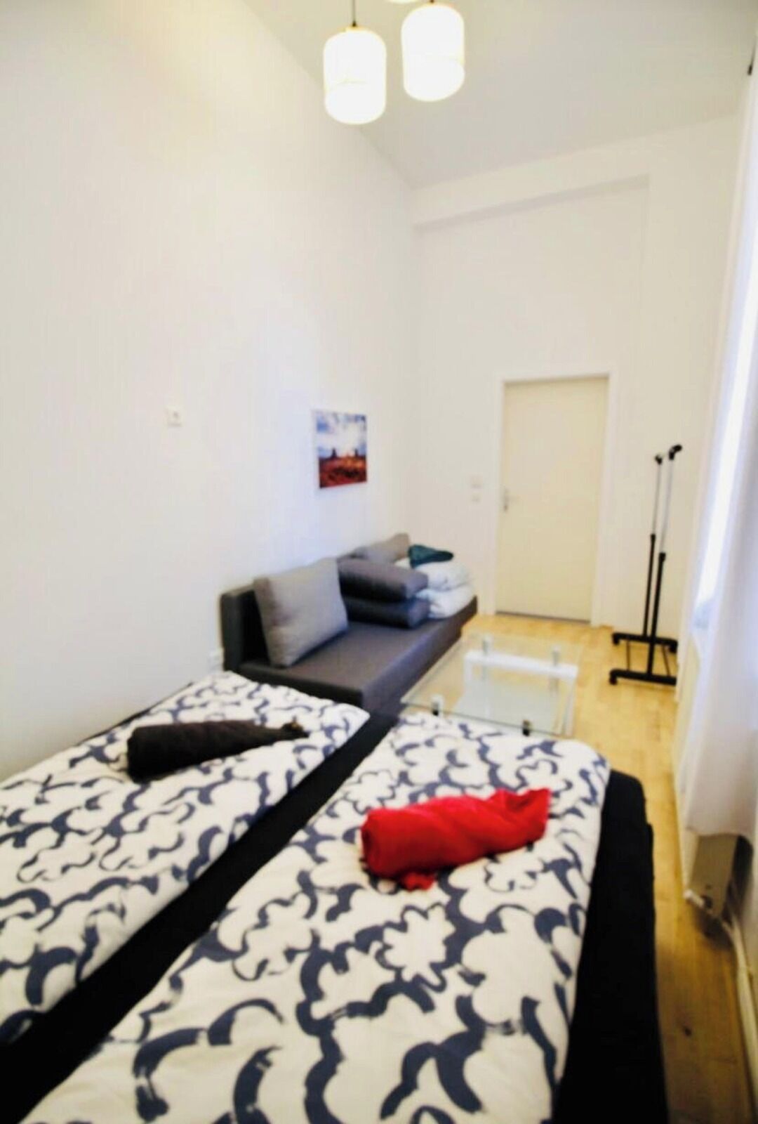 A room with a bed, a sofa, a small table, and a door.