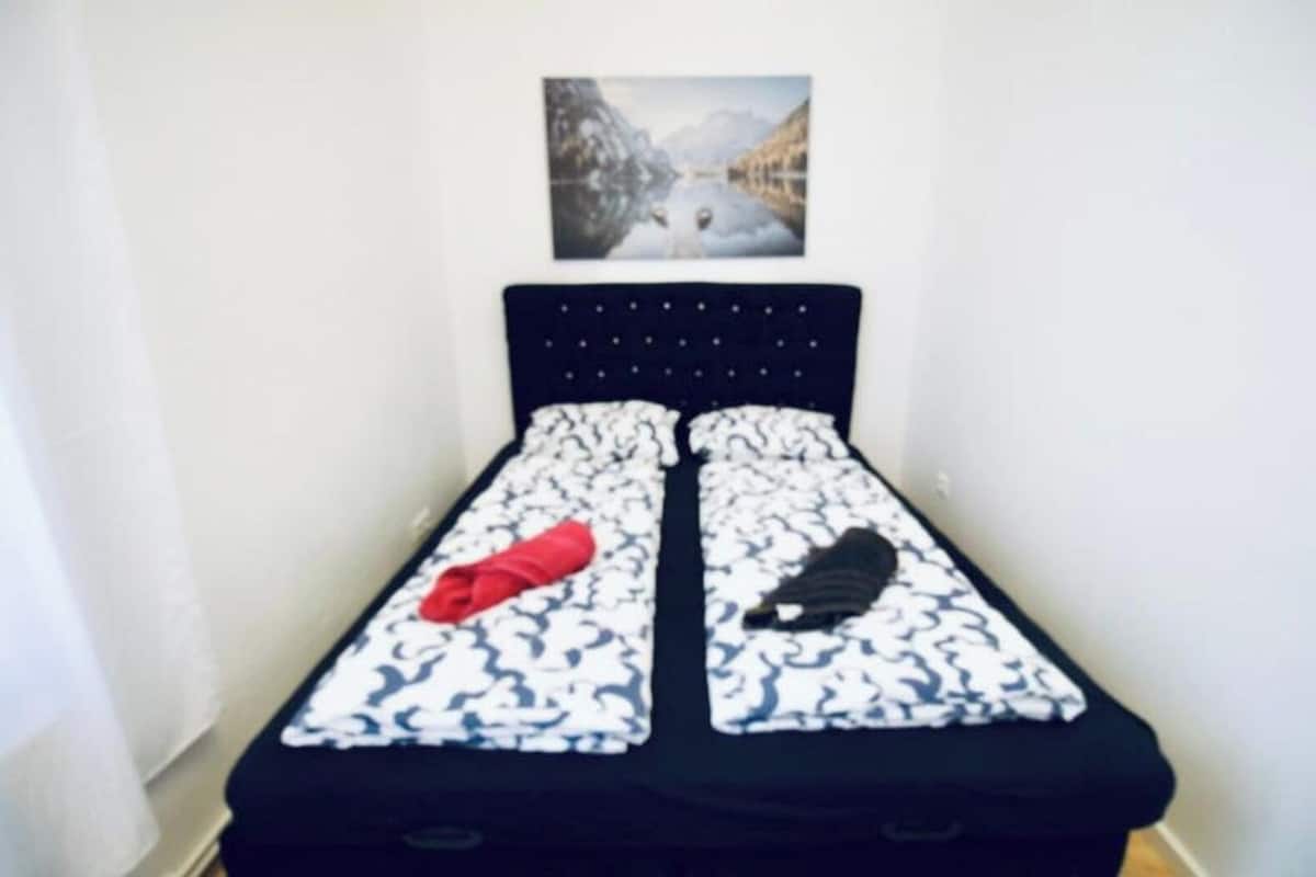 A small, single-bed room with a simple headboard and a framed picture on the wall.