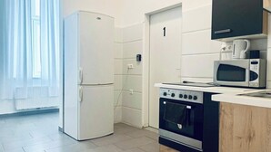 Eine kleine Küche mit Kühlschrank, Backofen, Mikrowelle und Schrank.