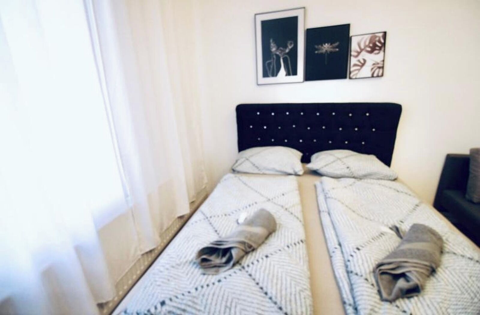 A neatly made bed with a striped blanket and two towels folded at the foot.
