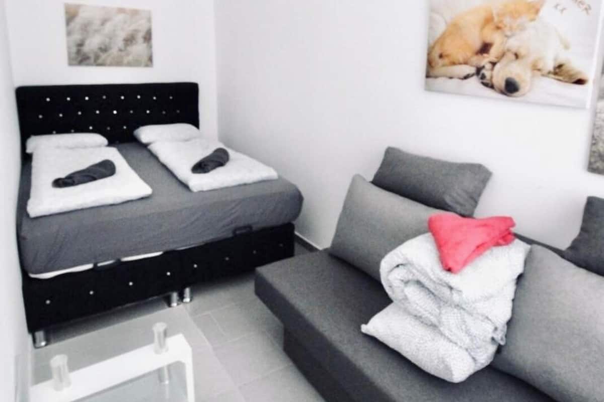A modern bedroom with a bed, a sofa, and a small table.
