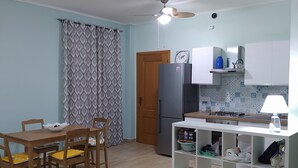 Una cocina compacta con mesa, sillas, refrigerador y estufa a gas.