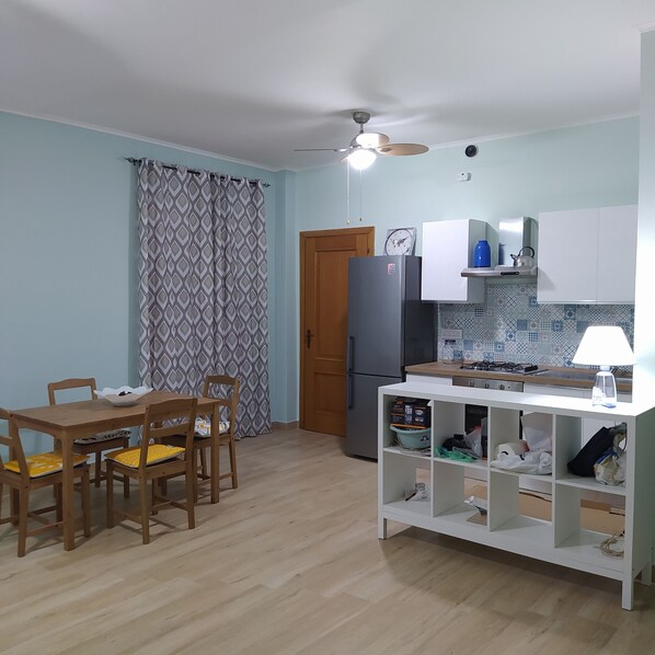 Una cocina compacta con mesa, sillas, refrigerador y estufa a gas.