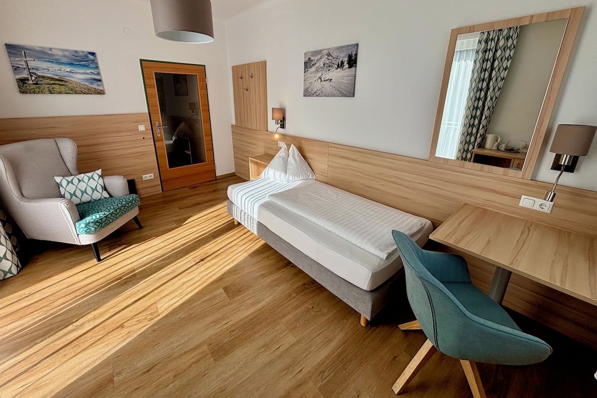 Hotellihuone, jossa on sänky, työpöytä, tuoli, vaatekaappi ja peili.