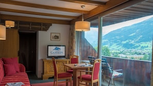 Un coin repas avec une table et des chaises, un canapé et une vue sur les montagnes.