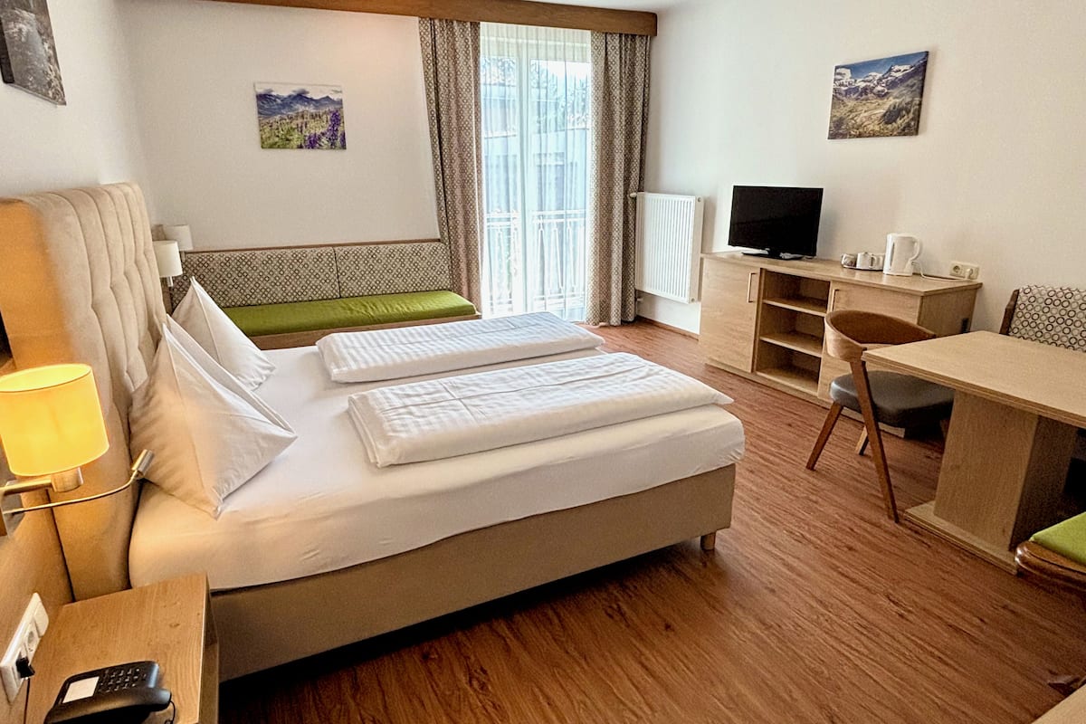 Hotellihuone, jossa on sänky, työpöytä, tuoli, televisio ja ikkuna, jossa on verhot.