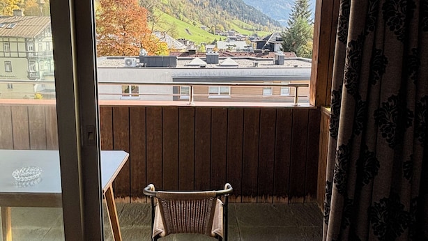 Une pièce avec un plafond en bois, une vue sur un paysage montagneux, une chaise et une table.