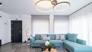 En moderne stue med en turkis sofa, to runde borde og en sort dør.