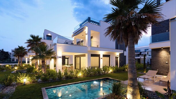 Et moderne hus med flere etager, swimmingpool, udendørs siddepladser og en velplejet have.