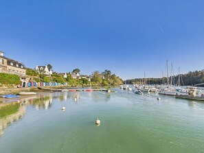 Uma marina com barcos, superfície de água calma e edifícios ao longo da costa.