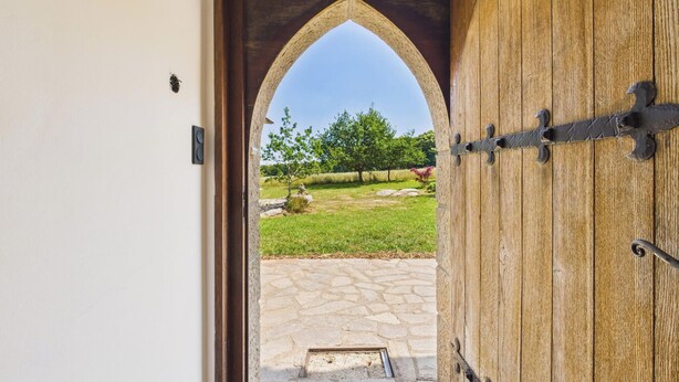 Une porte en bois ouverte, avec un chemin de pierres menant à l’extérieur.