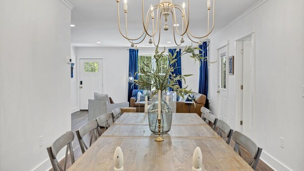 Une salle à manger avec une table en bois, des chaises, un lustre et un vase avec des plantes.