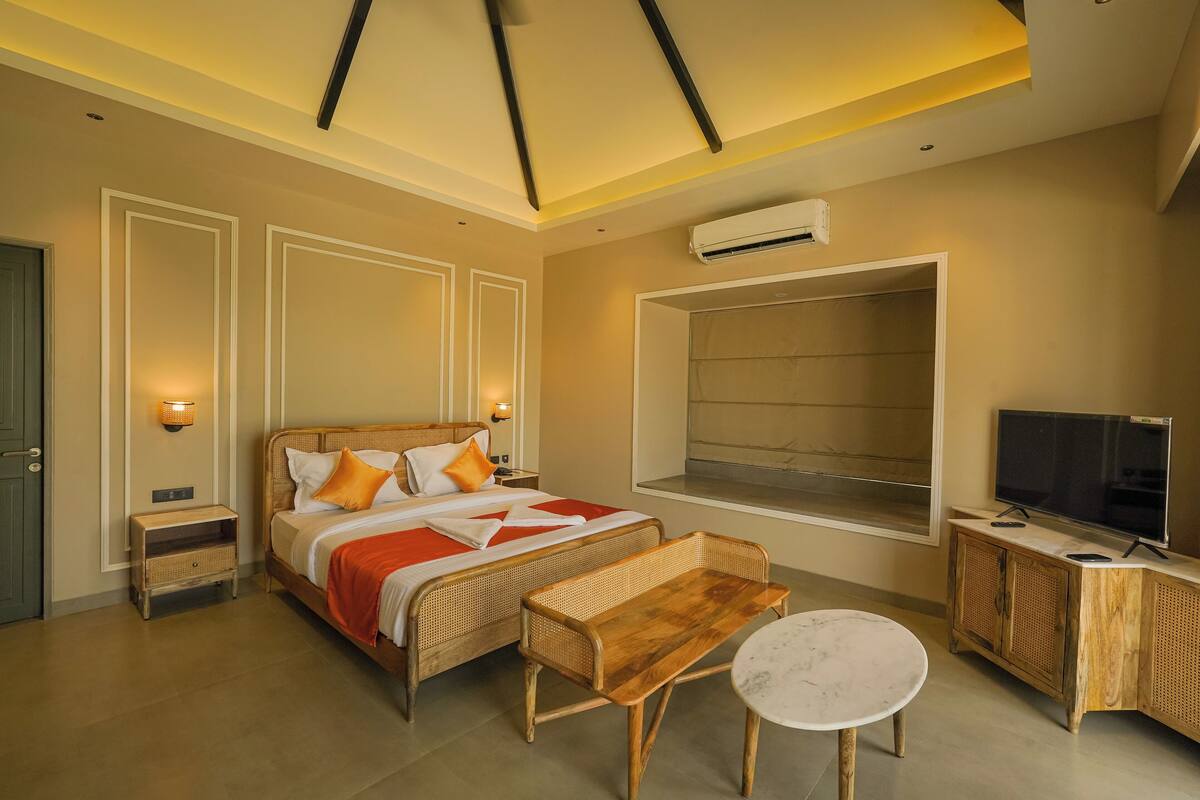 A hotel room with a bed, bedside table, TV, and a window.