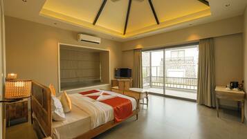 A modern hotel room with a large bed, a TV, a desk, and a balcony with a view.