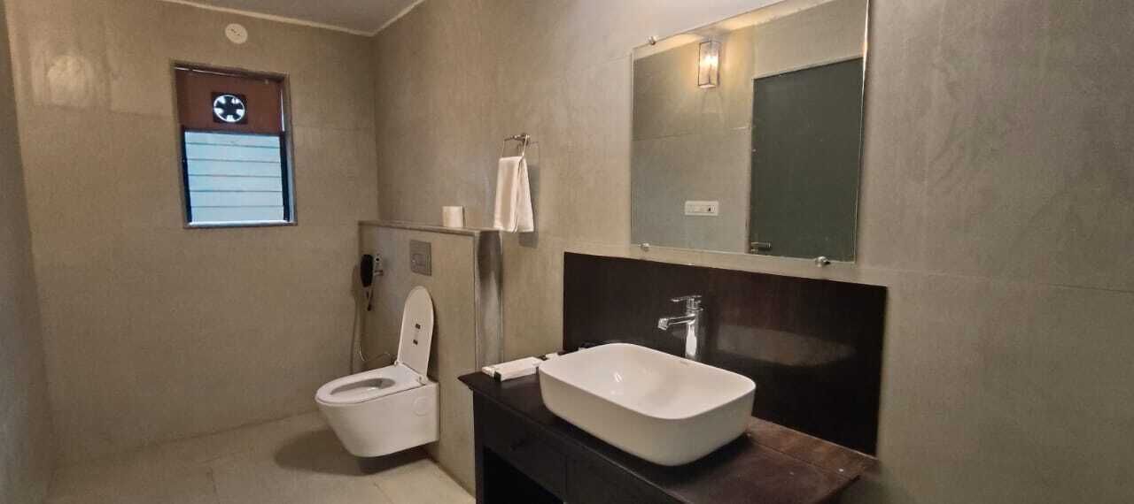 Une salle de bain équipée de toilettes, d’un lavabo, d’un miroir et d’une petite fenêtre avec une horloge.