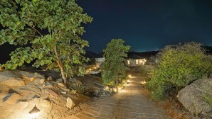 Un chemin de pierres qui mène à un bâtiment d’où l’on peut admirer le ciel nocturne.