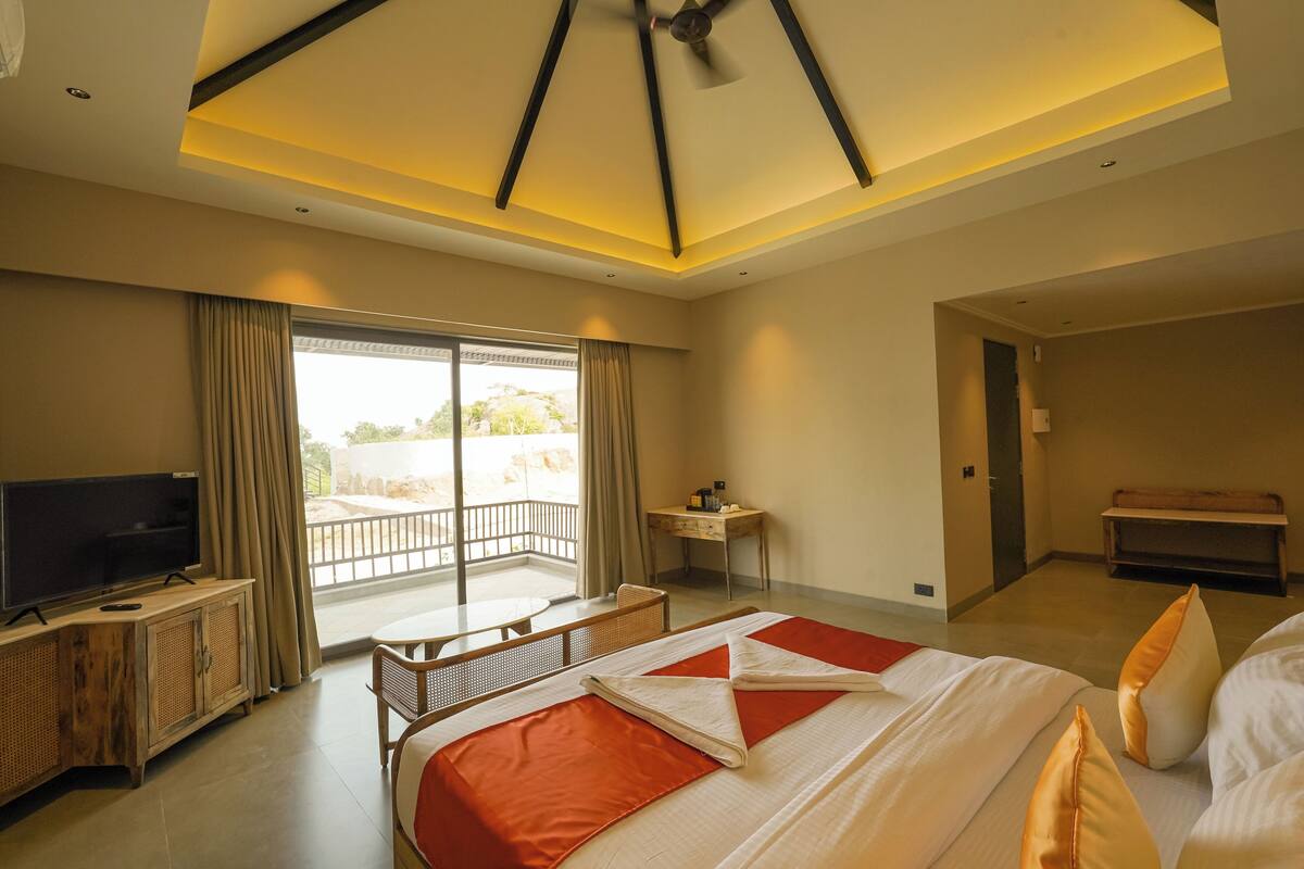 A hotel room with a bed, a TV, a desk, and a balcony.