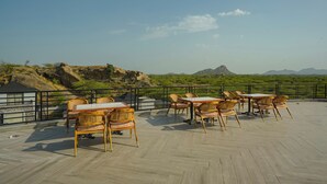 Une terrasse avec des sièges extérieurs et une vue sur un paysage montagneux.