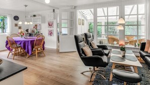 Ein geräumiges Wohnzimmer mit Essbereich, großen Fenstern und Blick ins Grüne.