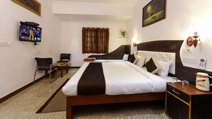 Een hotelkamer met een groot bed, een televisie, een bureau en een stoel.