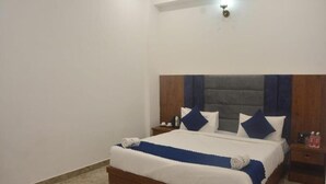 Een net opgemaakt bed met een houten hoofdbord, wit- en blauwe beddengoed en een marmeren vloer.
