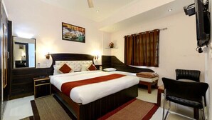 Een hotelkamer met een groot bed, een bureau, een stoel, een televisie en een plafondventilator.