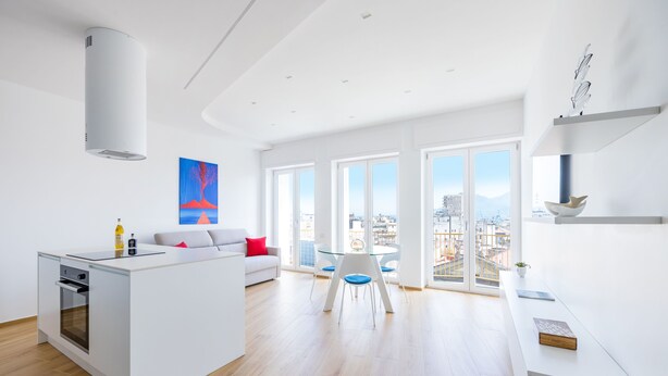 A modern kitchen with a built-in oven, a dining area with a glass table and chairs, and large windows offering a city view. - At Twenty-One: new apartment with exclusive panoramic views! (Napoli)