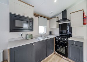 A modern kitchen with a microwave, toaster, sink, stove, and oven.