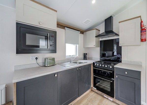 A modern kitchen with a microwave, toaster, sink, stove, and oven.