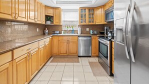 Una cocina moderna con armarios de madera, electrodomésticos de acero inoxidable y suelo de baldosas.
