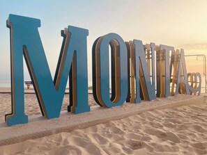 Large blue letters spelling "MONTE" on a beach.