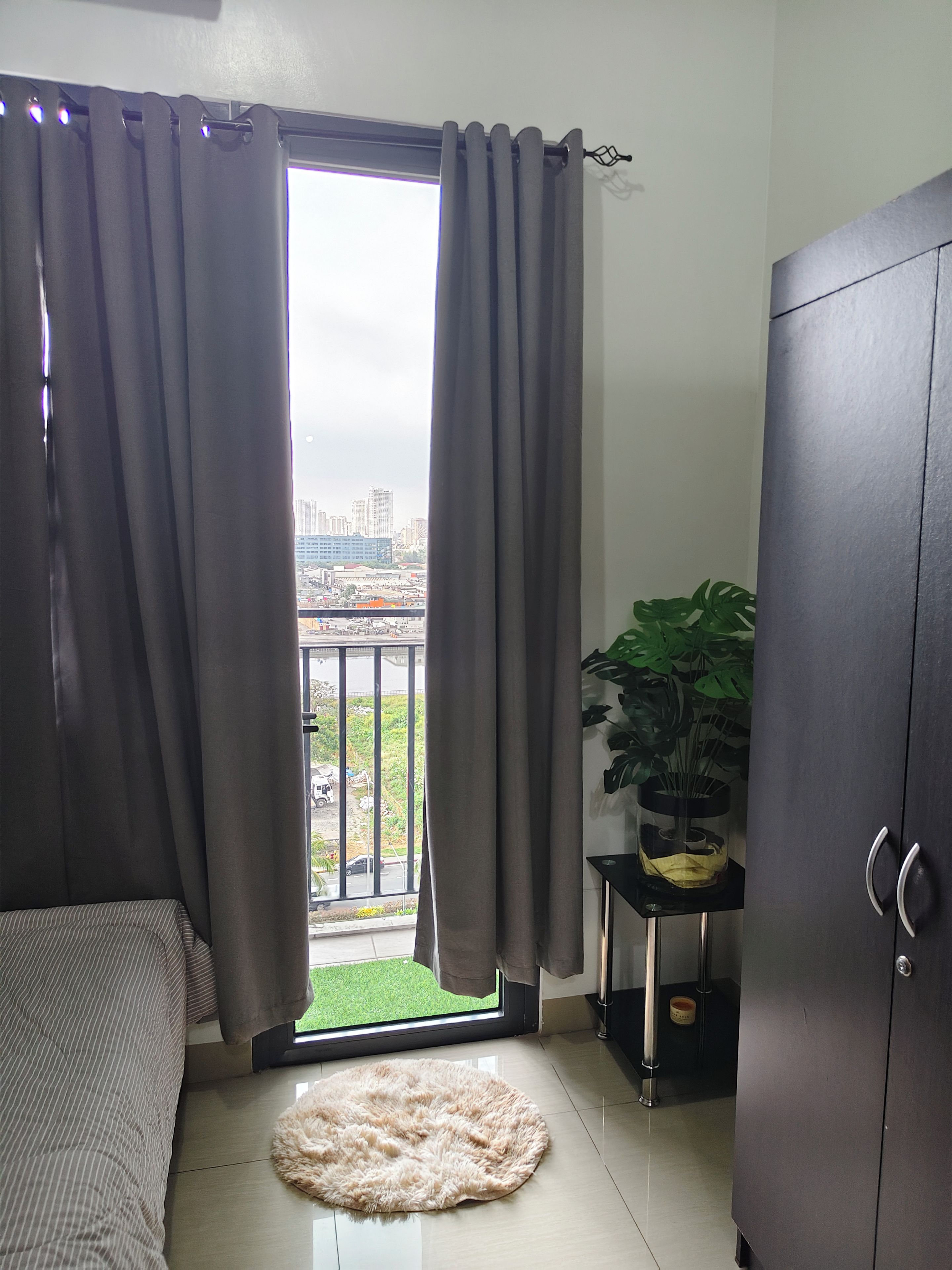 Une pièce comprenant un lit, un tapis rond, une armoire et une plante en pot.