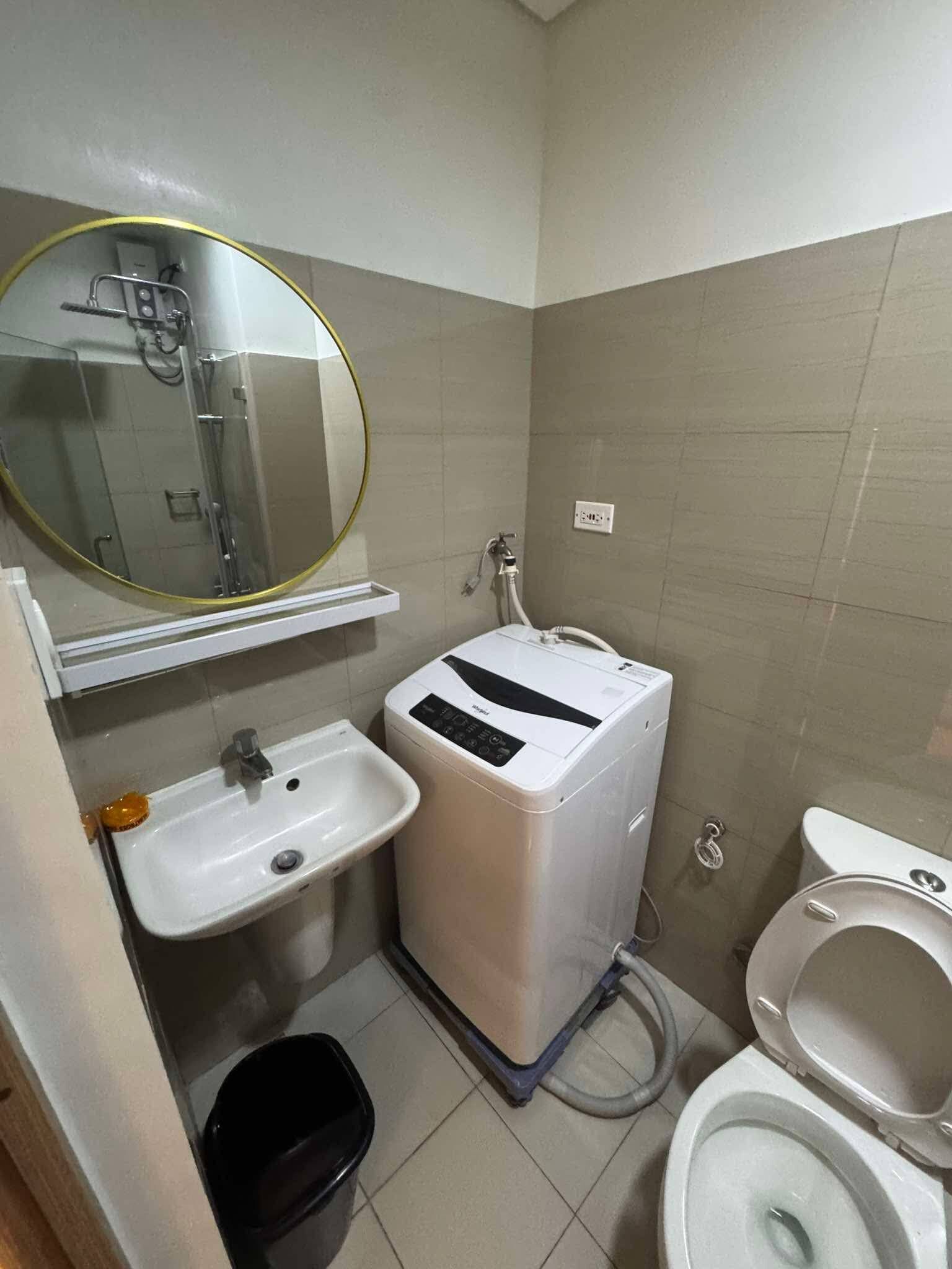 Et lille badeværelse med håndvask, toilet og vaskemaskine.