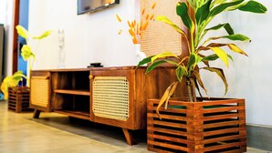 Ein modernes Interieur mit einer hölzernen Sitzbank, einem an der Wand befestigten Fernseher und Topfpflanzen.