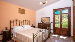 A bedroom with a bed, dresser, nightstand, and a door leading to a balcony.