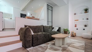 Un salon moderne avec un canapé, une table basse et un escalier menant à un niveau supérieur.