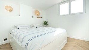 Une chambre à coucher avec un lit, une plante et une fenêtre.