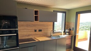 Une cuisine moderne dotée d’appareils électroménagers intégrés, d’un mur d’accent en bois, d’une grande fenêtre et d’une vue sur l’extérieur.