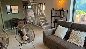 Un salon moderne avec un escalier, un coin repas et une vue sur un paysage montagneux.