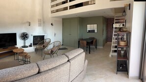 Un salon moderne avec un grand canapé, deux fauteuils, un téléviseur et une cheminée.