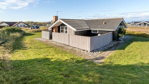 Een gelijkvloers huis met een schuin dak, een omheinde tuin en een schotelantenne.