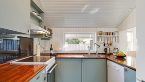 Een moderne keuken met een centraal eiland, een ingebouwde oven en een raam voor natuurlijk licht.
