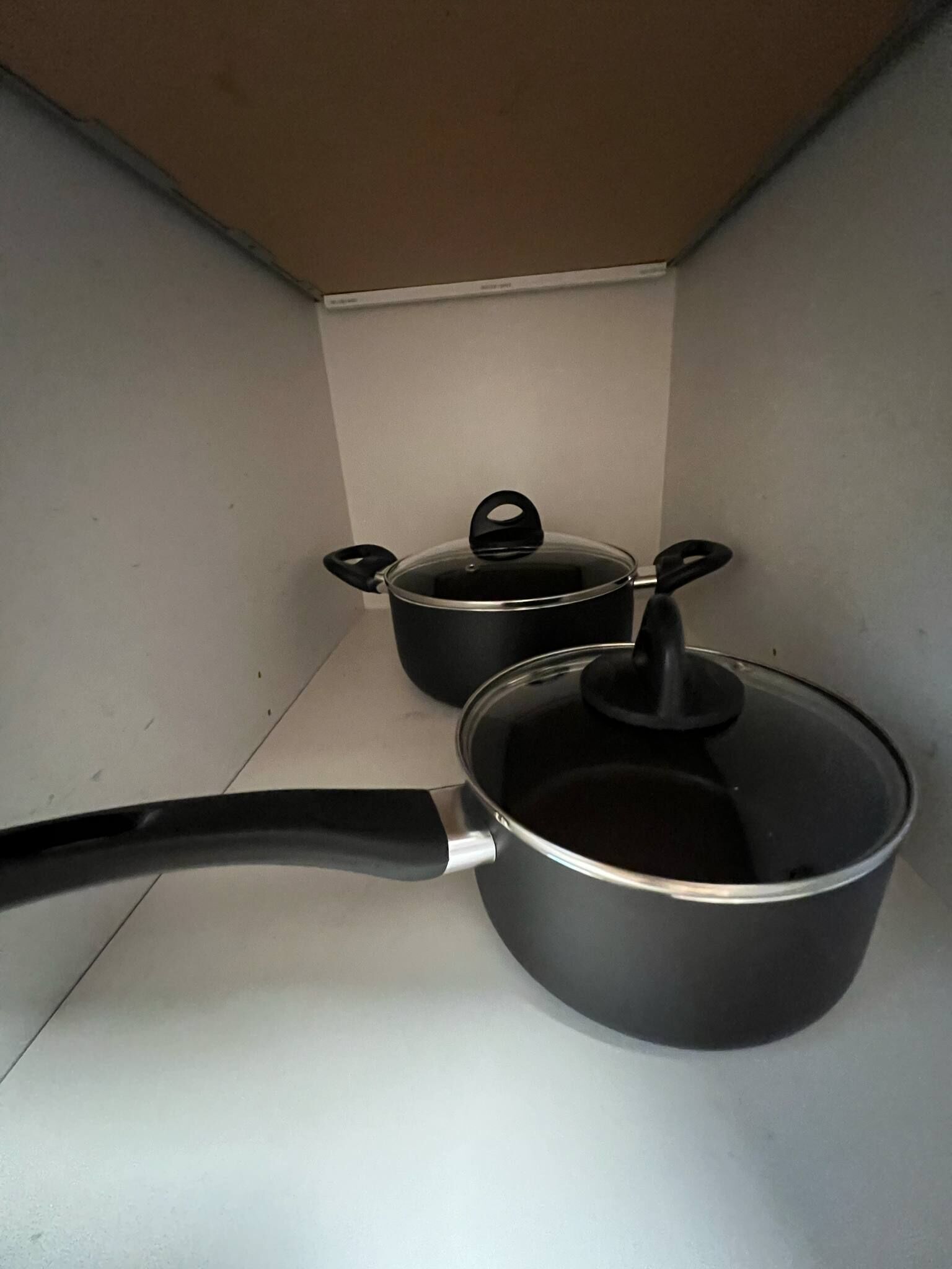 A kitchen with two pots and a pan on a white countertop.