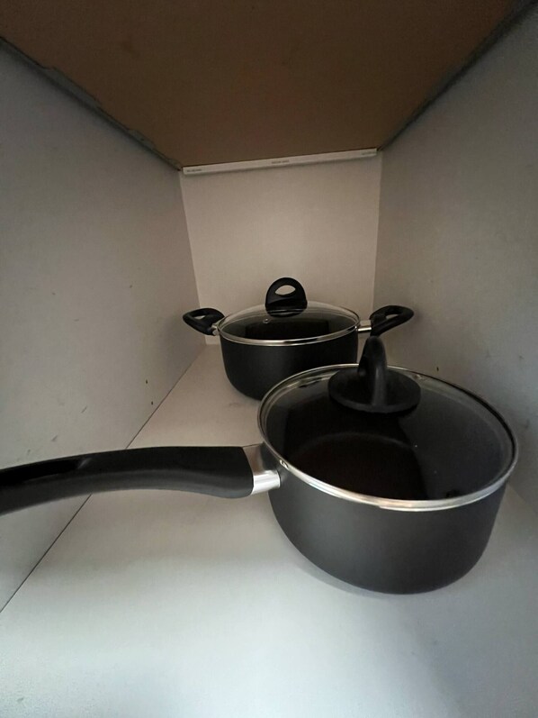Uma cozinha com duas panelas e uma frigideira sobre um balcão branco.