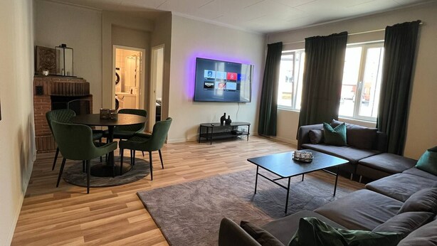 Una sala de estar moderna con una televisión de pantalla plana, un comedor con una mesa redonda y sillas, un sofá y una mesa de centro.