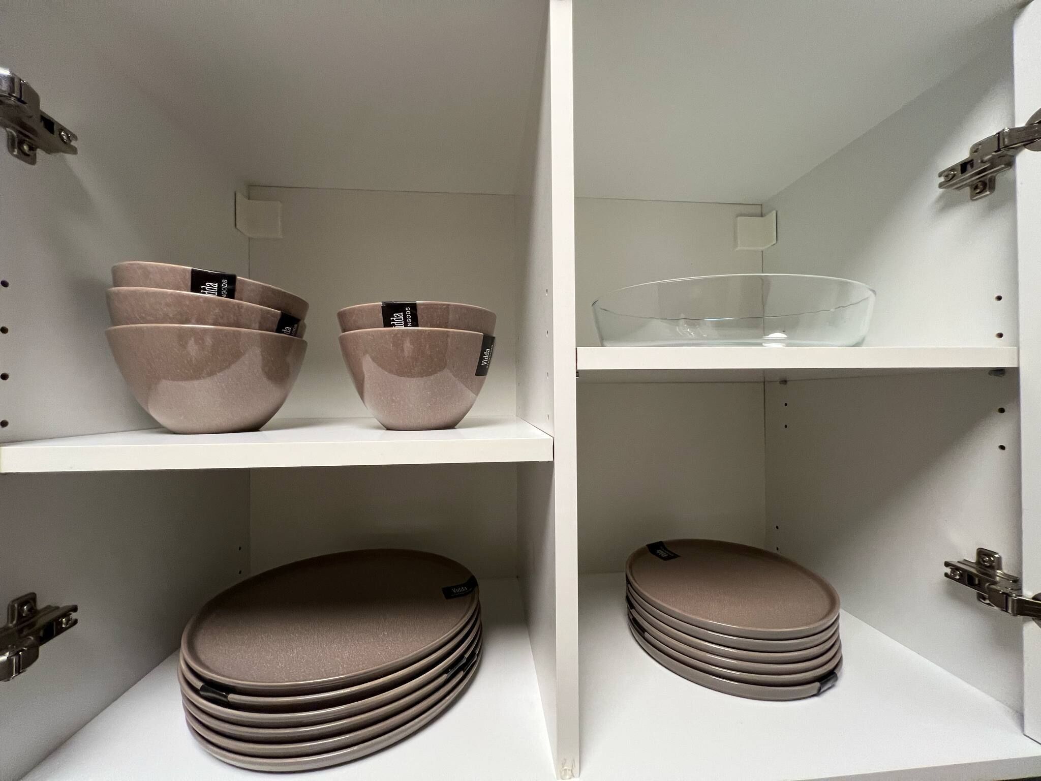 A display of kitchenware including bowls and plates on white shelves.
